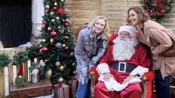 An Alpine Holiday movie: Two sisters stand either side of Santa to pose for a photo