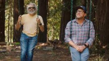 Andre is an Idiot: Two men swinging in a forest, one standing, one sitting, trees in the background.