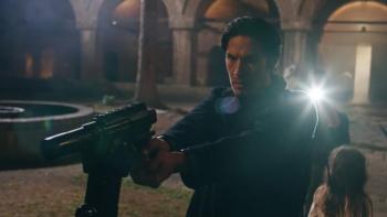 Angels Fallen: Michael Teh holds a gun while wearing a black outfit with a lens flare over his shoulder