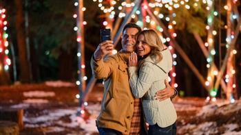 Another Sweet Christmas movie: Cameron Mathison and Candace Cameron Bure stand taking a phone selfie pic