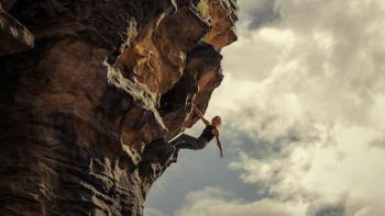 Apex: Charlize Theron on the side of a rock wall.