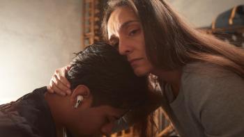 At the Gates Movie: A woman comforts her teen son with an embrace