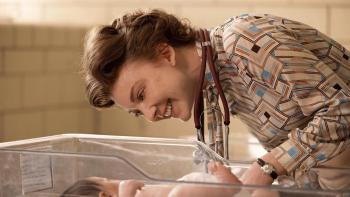 Audrey's Children movie: Natalie Dormer smiles and leans down over a baby in a hospital infant crib