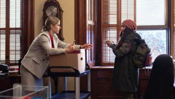 Autumn and the Black Jaguar movie: A female teacher holds a cell phone, looking with alarm at a teen girl holding a hedgehog