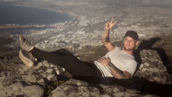 Avicii - I'm Tim: Tim leaning on a rock with a view behind.