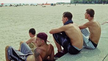 Beach Rats: Harris Dickinson and three other young White men sit together shirtless looking out over the beach.