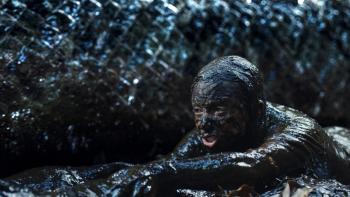 Beware Boiúna movie: A person covered in mud next to a large, scaly creature