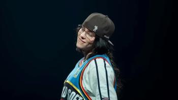 Billie Eilish Hit Me Hard and Soft movie: Eilish in a cap, smiling and wearing a colorful jersey while performing