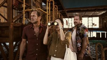 The Black Demon Movie: Paul, Ines, and Chato stand on the deck of the oil rig while Ines looks through binoculars at something concerning at sea