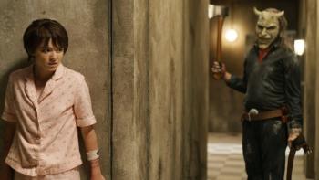 Black Phone 2 Movie: Gwen, wearing pink pajamas, hides from the menacing Grabber, who wields an axe