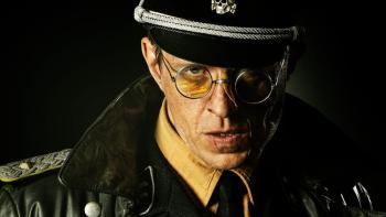 Blood & Gold: Close up of Nazi officer in hat and circle rimmed glasses center