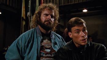 Bloodsport Movie: Bearded fighter Ray Jackson (Donald Gibb) looks on as Frank (Jean-Claude Van Damme) speaks to someone