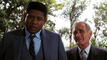 Bloodsport Movie: CID agents Rawlins (Forest Whitaker) and Helmer (Norman Burton) question someone in Hong Kong