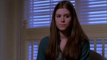 Urban Legend—Bloody Mary: Young woman with long hair looks reflective as she sits on her bed in partial darkness