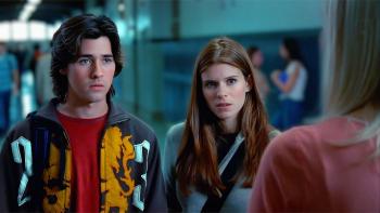 Urban Legend—Bloody Mary: A young White man and woman stand in a college hallway, speaking to someone just out of shot