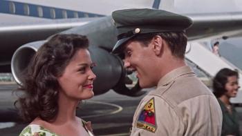 Blue Hawaii: Joan Blackman and Elvis Presley smile at each other in front of a plane