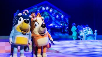 Bluey's Big Play: Bluey's dad and mum stand together on stage while Bluey and Bingo have gone to bed in the background