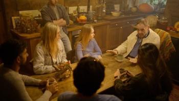 Bone Keeper: John Rhys-Davies talks seriously to a group of young people, as they sit around a table