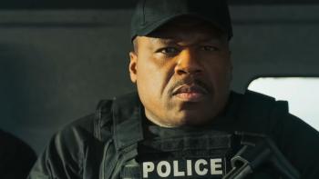 Boneyard movie: Curtis "50 Cent" Jackson in police vest and black baseball cap sits in truck