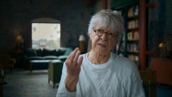 Breakdown: 1975 movie: Screenwriter Joan Tewkesbury talks to the camera in a luxurious office, couch and book-filled bookcase behind her