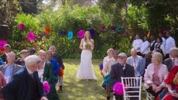 Bride of the Year: Bride walking down an outdoor aisle, guests seated, with colorful decorations.