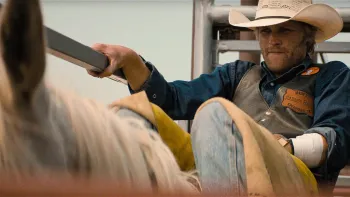Broke movie: Wyatt Russell in rodeo gear and cowboy hat sits atop a bull right before being released into the rodeo arena