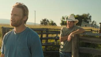 Broke movie: Wyatt Russell in blue t-shirt left talks with Dennis Quaid in white cowboy hat behind him while on their farm, next to a horse paddock