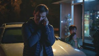 Brothers Movie: Moke (Josh Brolin) leans on his car and talks on the phone, while Jady looks on from the background