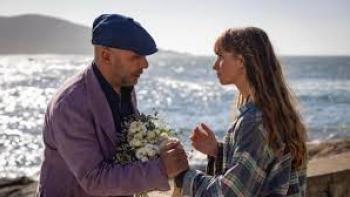 Buen Camino Movie: Man giving flowers to woman by the sea.