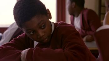 Bullet Boy: Luke Fraser sits at school desk looking to one side while wearing a red sweatshirt and white shirt