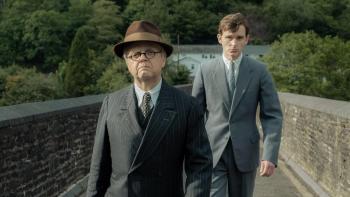 Mr. Burton: Toby Jones and Harry Lawtey walks over a bridge wearing suits and serious expressions