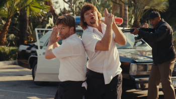 Busboys movie: Two men pose comically, making finger guns beside a police car