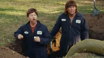 Busboys movie: Two men in dark uniforms stand beside a hole in a grassy area