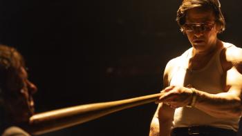 By Any Means Movie: Wearing dark glasses and a tank top, Scarpa holds a baseball bat to the face of a man he's torturing