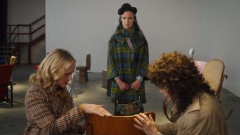 By Design Movie: Camille stands and looks at a beautiful chair as her friends Lisa and Irene touch its wooden surface