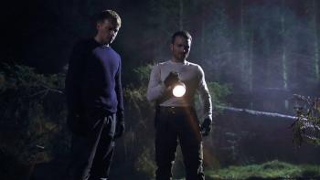 Calibre: Two White men in the forest at night, one holding a torch