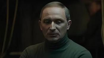 Canary Black: Goran Kostic in a dark room wearing a green polar neck while looking down