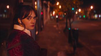 Cat Person Movie: Emilia Jones walks down a desolate street at night, wearing headphones and looking over her shoulder