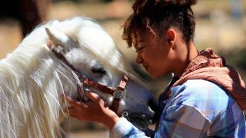 Legend of Catclaws Mountain: a biracial girl snuggles a mini white pony
