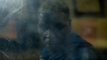 Caterpillar movie: David Taylor stands at a dirty window, looking down at the floor