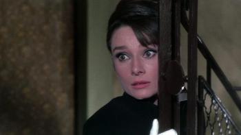 Charade: Audrey Hepburn peers from behind a banister, looking frightened