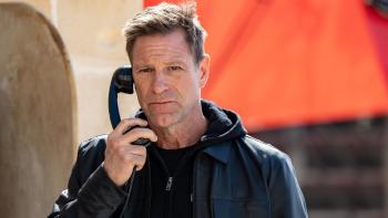 Classified movie: Aaron Eckhart in black leather jacket center speaks into payphone outdoors