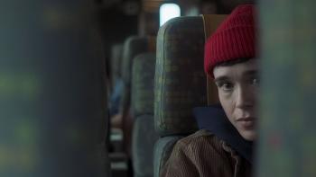 Close to You movie: Sam (Elliot Page), wearing a beanie hat, looks at something while on a train