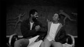 Color Book: Black father and child smiling and shaking hands on a bench indoors.