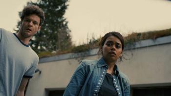 Companion Movie: Josh (Jack Quaid) and Kat (Megan Suri) look down at an open car trunk, registering shock and/or disgust