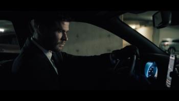 Crime 101 Movie: In a black suit and gloves, Mike (Chris Hemsworth) is serious and focused behind the wheel of his car