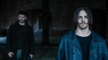 Dampyr: Two White men stand in a deserted brick building surrounded by darkness