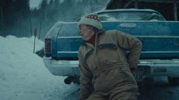 Dead of Winter movie: Emma Thompson, in coveralls and a knit hat, hides behind a blue Chevy El Camino on a snowy day