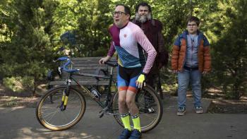 Dear Santa movie: Jack Black dressed as the devil stands smirking next to a 10-year-old boy near a cyclist holding his legs together