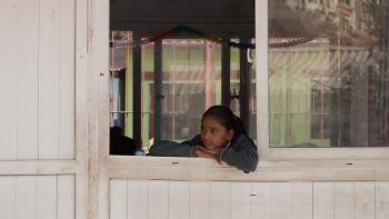 Dear Thirteen movie: Arti looks out schoolhouse window, wearing an olive green sweater